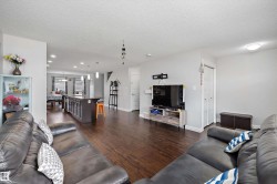 Open-concept living area featuring wood-finish flooring, a kitchen island with pendant lighting, and recessed ceiling lights - 