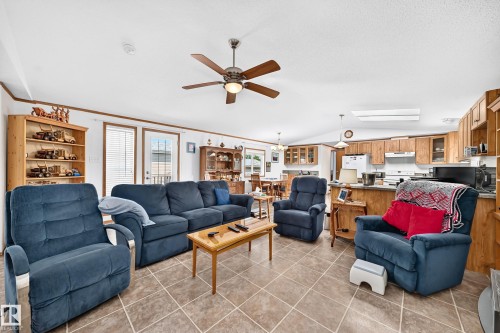 Open-concept living area featuring tile flooring, a ceiling fan, and white walls with wood trim - #225 3400 48 St, Stony Plain, AB - Indoor Photo Showing Living Room