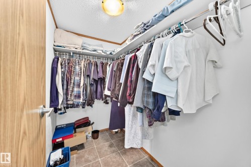 Walk-in closet featuring an overhead light fixture, multiple upper storage shelves, and ample hanging rod space - #225 3400 48 St, Stony Plain, AB - Indoor With Storage