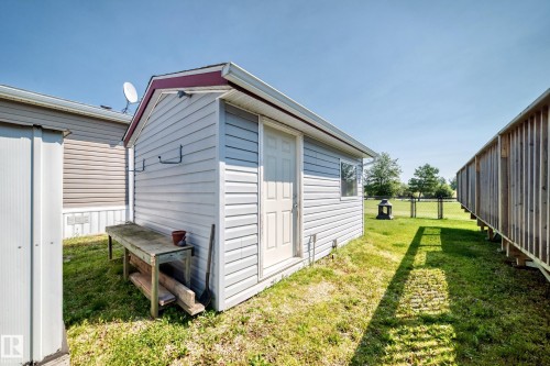 Detached utility shed with light-colored siding and a contrasting red roof trim - #225 3400 48 St, Stony Plain, AB - Outdoor With Exterior