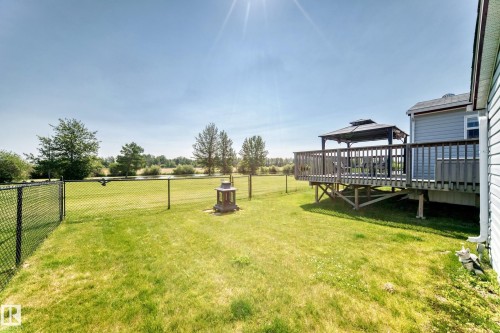 Expansive backyard featuring a manicured lawn, full perimeter fencing, and a raised wooden deck with a gazebo - #225 3400 48 St, Stony Plain, AB - Outdoor With Deck Patio Veranda