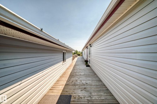 Hardscape wooden walkway between two structures featuring light-colored siding - #225 3400 48 St, Stony Plain, AB - Outdoor With Exterior
