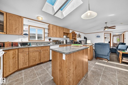 Kitchen featuring wood-finish cabinetry, a central island with countertop, and a double basin sink - #225 3400 48 St, Stony Plain, AB - Indoor Photo Showing Kitchen With Double Sink