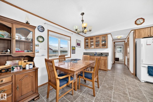 Dining area featuring tile flooring, a window providing natural light, a ceiling-mounted light fixture, and wood-finish cabinetry - #225 3400 48 St, Stony Plain, AB - Indoor Photo Showing Dining Room