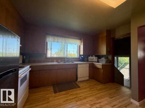 Kitchen with wood-finish flooring, wood cabinetry, and a skylight - 9908 96A Avenue, Fort Saskatchewan, AB - Indoor Photo Showing Kitchen With Double Sink