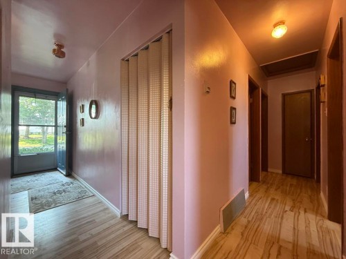 Hallway featuring light wood-finish flooring, a full-lite storm door, and a folding accordion-style door - 9908 96A Avenue, Fort Saskatchewan, AB - Indoor Photo Showing Other Room