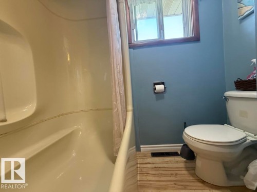Bathroom featuring a built-in tub/shower combination, toilet, and a window with wood trim - 9908 96A Avenue, Fort Saskatchewan, AB - Indoor Photo Showing Bathroom