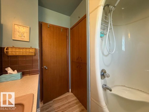 White shower-over-tub unit with chrome fixtures - 9908 96A Avenue, Fort Saskatchewan, AB - Indoor Photo Showing Bathroom
