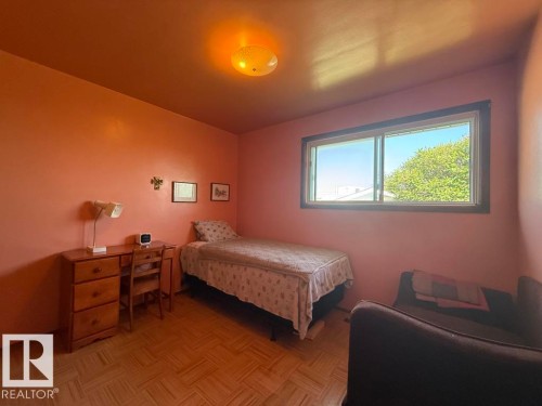 Room featuring a horizontal sliding window, ceiling-mounted light fixture, and wood-finish parquet flooring - 9908 96A Avenue, Fort Saskatchewan, AB - Indoor Photo Showing Bedroom