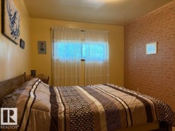 Interior room featuring a window with sheer curtains, a light-colored ceiling, and a brick-patterned accent wall - 