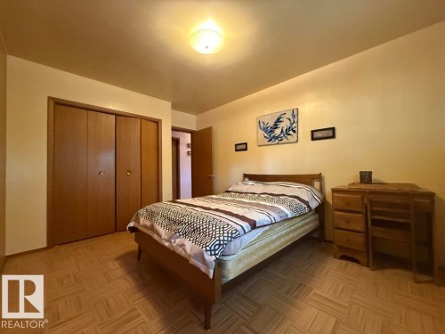 Bedroom featuring parquet wood-finish flooring, light-toned walls, and a ceiling-mounted light fixture - 9908 96A Avenue, Fort Saskatchewan, AB - Indoor Photo Showing Bedroom