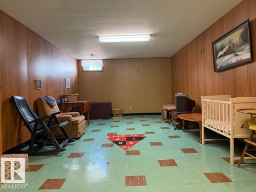 Spacious room featuring wood-finish paneling, a paneled ceiling, and a window for natural light - 9908 96A Avenue, Fort Saskatchewan, AB - Indoor Photo Showing Basement