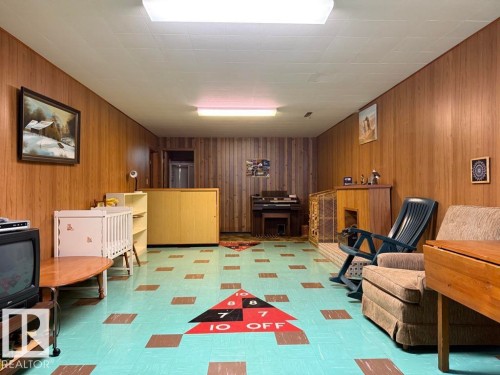Recreation room featuring wood-finish wall paneling, a drop ceiling with recessed lighting, and resilient flooring with a geometric pattern - 9908 96A Avenue, Fort Saskatchewan, AB - Indoor Photo Showing Other Room
