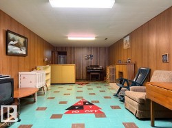 Recreation room featuring wood-finish wall paneling, a drop ceiling with recessed lighting, and resilient flooring with a geometric pattern - 