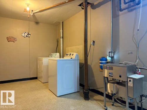 Dedicated utility space featuring a washer and dryer, exposed ceiling pipes, and light-toned walls - 9908 96A Avenue, Fort Saskatchewan, AB - Indoor Photo Showing Laundry Room