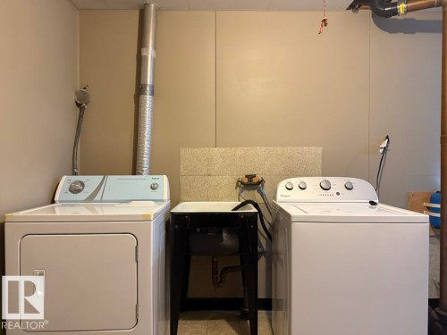 Dedicated utility area featuring a laundry sink, exposed copper plumbing, and durable wall paneling - 9908 96A Avenue, Fort Saskatchewan, AB - Indoor Photo Showing Laundry Room