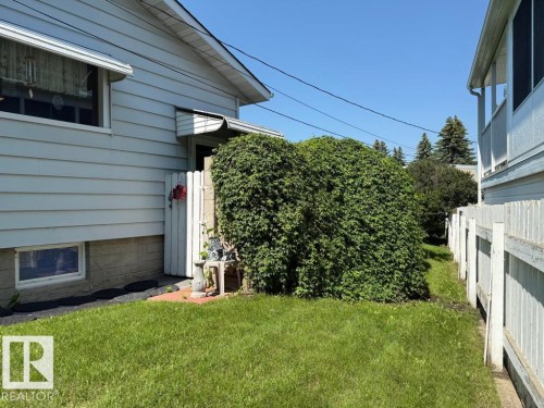 Manicured lawn surrounding the property, featuring a white picket fence and mature perimeter hedging - 9908 96A Avenue, Fort Saskatchewan, AB - Outdoor With Exterior