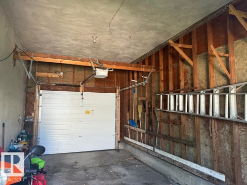 Interior garage featuring a white overhead door and exposed wood framing - 9908 96A Avenue, Fort Saskatchewan, AB - Indoor Photo Showing Garage
