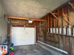 Interior garage featuring a white overhead door and exposed wood framing - 