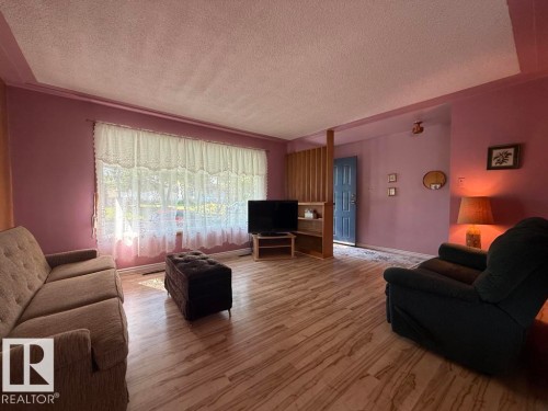 Bright living area featuring wood-finish flooring and a large window - 9908 96A Avenue, Fort Saskatchewan, AB - Indoor Photo Showing Living Room