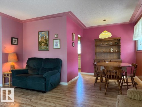 Open-concept living and dining areas featuring wood-finish flooring, vibrant wall tones, and white trim - 9908 96A Avenue, Fort Saskatchewan, AB - Indoor
