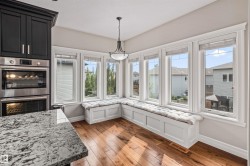 Built-in window seating with cushions, hardwood flooring, and a stainless steel double oven - 