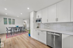 Contemporary kitchen featuring white cabinetry, a white subway tile backsplash, and light-tone wood-finish flooring - 
