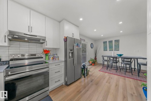 Modern kitchen featuring white shaker cabinetry, stainless steel appliances, a white tile backsplash, and light wood-finish flooring extending into the dining area - 4119 18 Avenue Nw, Edmonton, AB - Indoor Photo Showing Kitchen