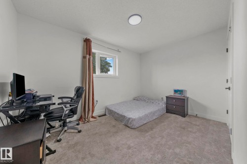 Carpeted room featuring a single window with curtains, white walls, and a ceiling-mounted light fixture - 4119 18 Avenue Nw, Edmonton, AB - Indoor Photo Showing Office