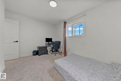 Bright room featuring a window with natural light, light gray wall-to-wall carpeting, white walls, and a white interior door with black hardware - 4119 18 Avenue Nw, Edmonton, AB - Indoor