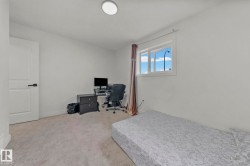 Bright room featuring a window with natural light, light gray wall-to-wall carpeting, white walls, and a white interior door with black hardware - 