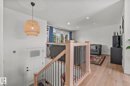 Entryway with a light wood-finish staircase featuring black metal spindles and a wood-finish newel post - 4119 18 Avenue Nw, Edmonton, AB - Indoor Photo Showing Other Room