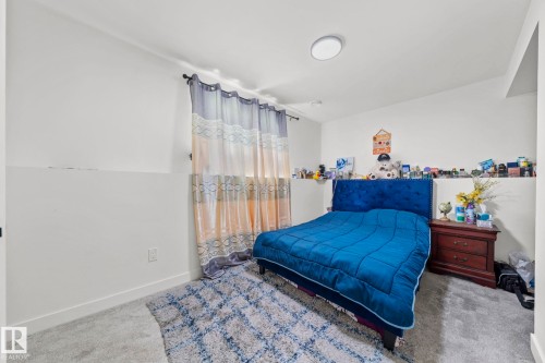 Carpeted room featuring a window with rod and curtains, a ceiling-mounted light fixture, and white wall finishes - 4119 18 Avenue Nw, Edmonton, AB - Indoor Photo Showing Bedroom