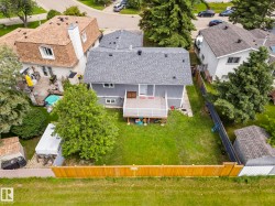 Private backyard featuring a wooden deck, mature trees, a wooden privacy fence, and a storage shed - 