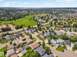 Residential area featuring a mix of single-family homes and multi-story buildings, bordered by extensive green spaces - 