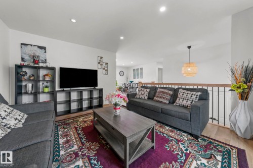 Open-concept living space with light wood-finish flooring, recessed lighting, and a modern wood and iron railing - 4119 18 Avenue Nw, Edmonton, AB - Indoor Photo Showing Living Room