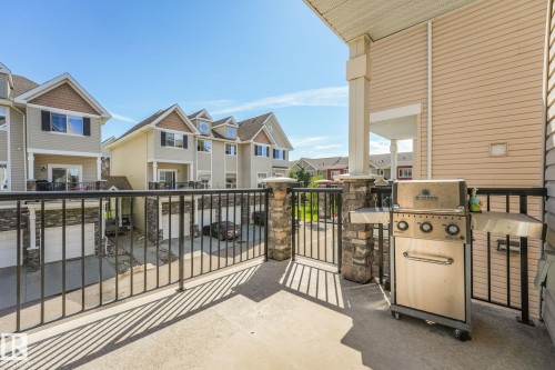 Concrete patio featuring a stone-clad balustrade, metal railings, and a covered portico - #16 7293 South Terwillegar Dr Nw, Edmonton, AB - Outdoor With Balcony With Exterior