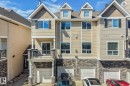 Multi-level townhouse exterior featuring stacked stone accents, neutral siding, a private balcony with black railings, a second-story sliding glass door, and a ground-level attached garage - #16 7293 South Terwillegar Dr Nw, Edmonton, AB  - Outdoor With Facade 