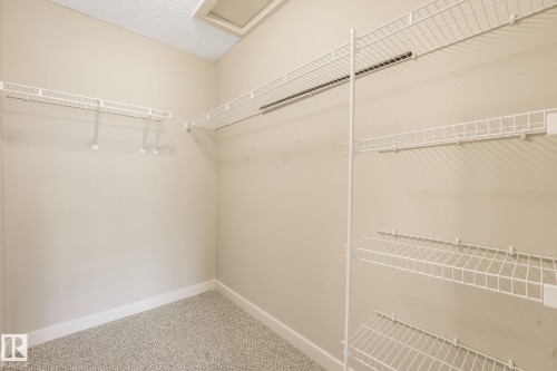 Spacious walk-in closet featuring wire shelving, hanging rods, and light-colored carpeting - #16 7293 South Terwillegar Dr Nw, Edmonton, AB - Indoor With Storage