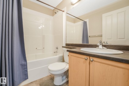 Full bathroom featuring a tub/shower combination with white surround, a toilet, a vanity with a laminate countertop, and a large wall-mounted mirror - #16 7293 South Terwillegar Dr Nw, Edmonton, AB - Indoor Photo Showing Bathroom