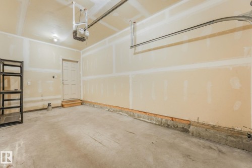 Spacious garage featuring a concrete floor, light-toned walls, and an overhead garage door opener mechanism - #16 7293 South Terwillegar Dr Nw, Edmonton, AB - Indoor