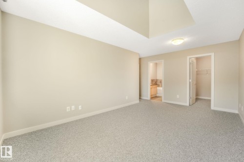 Spacious room featuring neutral carpeting, light beige wall finishes, a recessed ceiling detail, and a flush-mount ceiling light fixture - #16 7293 South Terwillegar Dr Nw, Edmonton, AB - Indoor Photo Showing Other Room