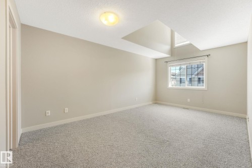 Spacious room with light-toned carpet flooring, a large window, and a vaulted ceiling feature - #16 7293 South Terwillegar Dr Nw, Edmonton, AB - Indoor Photo Showing Other Room
