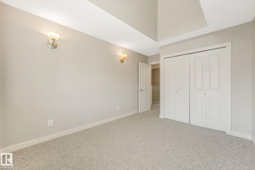 Neutral-toned room featuring a vaulted ceiling and wall sconces - #16 7293 South Terwillegar Dr Nw, Edmonton, AB - Indoor Photo Showing Other Room