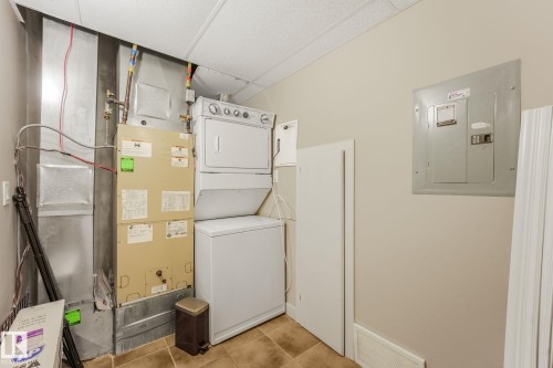 Utility area featuring a stacked washer and dryer, forced-air HVAC system, and electrical panels - #16 7293 South Terwillegar Dr Nw, Edmonton, AB - Indoor Photo Showing Laundry Room