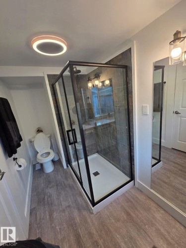 Modern bathroom featuring a glass-enclosed shower with black trim, a square shower drain, and dark grey subway tile surround - 10656 93 Street, Edmonton, AB 