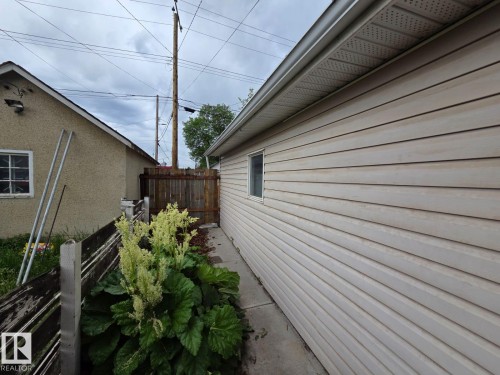 Side exterior showcasing horizontal siding and a white-framed window - 10656 93 Street, Edmonton, AB 
