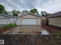 Detached garage featuring panel siding and a sectional overhead door - 