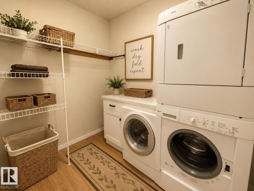 Dedicated laundry area featuring wood-finish flooring, white cabinetry with dark hardware, a stacked washer and dryer, and a countertop space - #302 8215 84 Av Nw, Edmonton, AB - Indoor Photo Showing Laundry Room