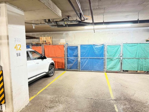 Dedicated parking space with painted yellow lines and adjacent storage units - #302 8215 84 Av Nw, Edmonton, AB - Indoor Photo Showing Garage